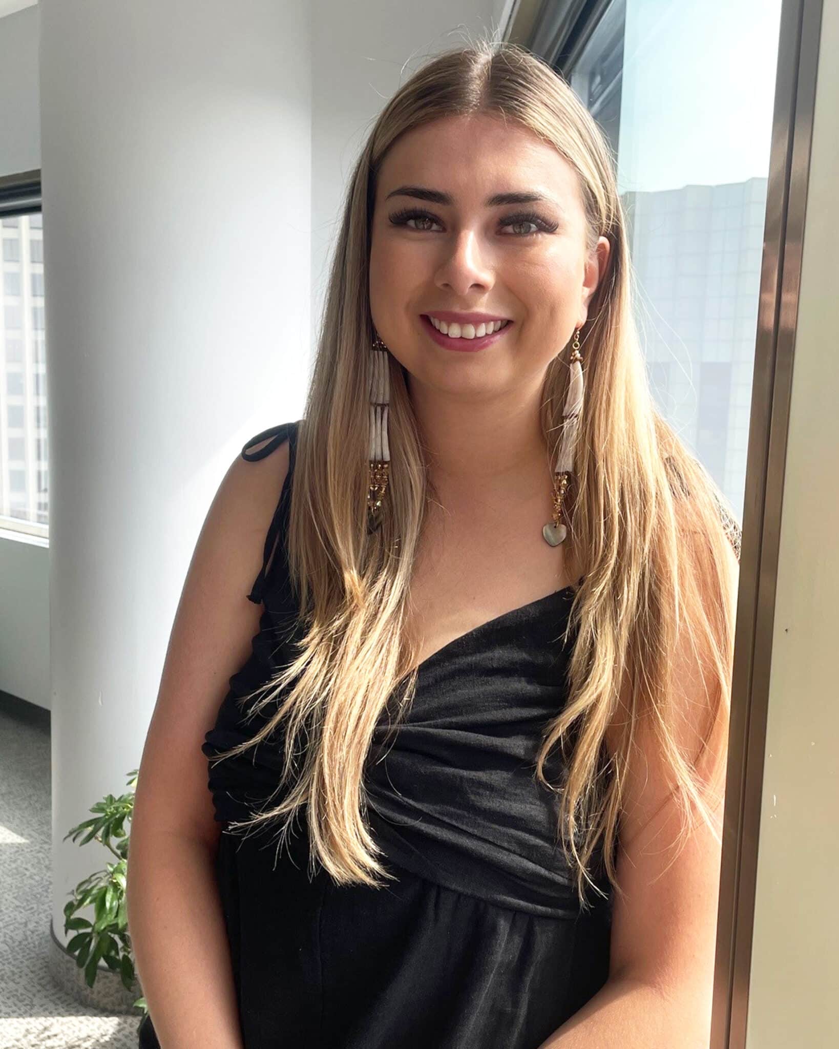 Photo of a young lady leaning against the window of a board room.